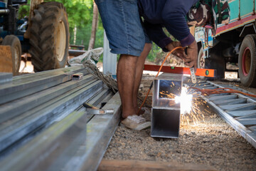 A man is sitting on the ground and working on a metal structure.