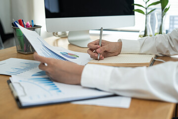 Business woman accountant working audit inspect calculating expense annual financial report balance sheet statement, doing finance making notes checking document and data analysis profit graph