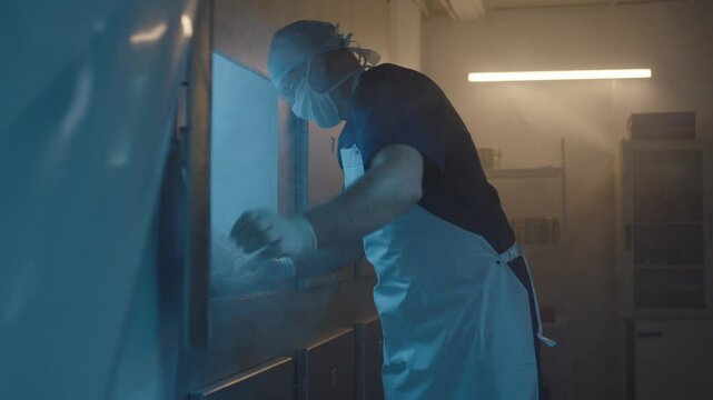 A Mortician taking the frozen body out from the freezer