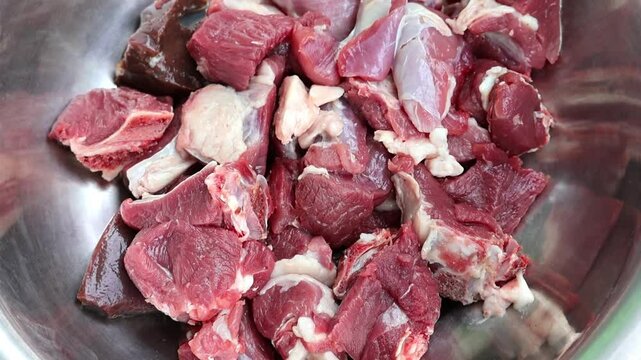 Fresh raw mutton slices in a silver bowl. Close-up of the vibrant red meat, ready for cooking.