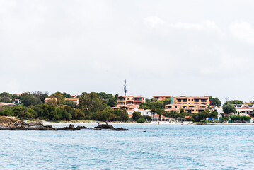 From the sandy shores of Di Bados, the rugged Sardinian coastline unfolds, where elegant villas nestle among the rocks and greenery. 