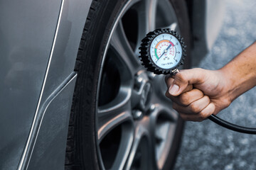 Hand car mechanic holding car tire pressure check equipment tool to checking low tire pressure...