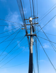 Obraz premium Picture of tangled network of power lines on a utility pole against a clear blue sky in usa