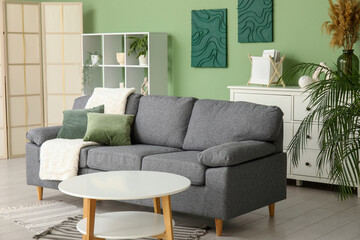 Interior of stylish living room with soft sofa, coffee table and shelving unit