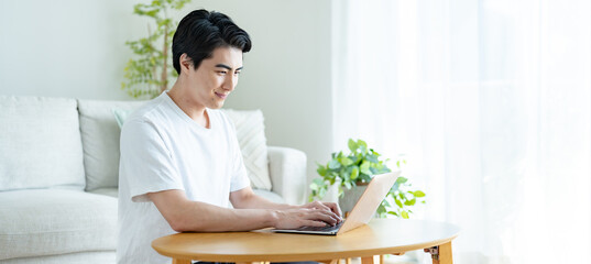 自宅でパソコン作業をする爽やかな男性