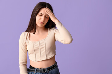 Young woman suffering from headache on lilac background