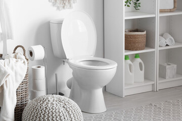 Toilet bowl, laundry basket and pouf in restroom