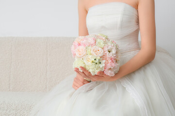 Beautiful bride with wedding bouquet sitting on sofa