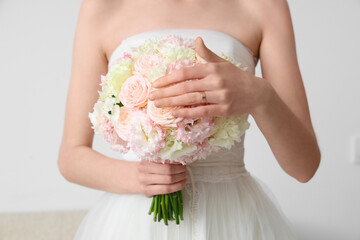 Beautiful bride with wedding bouquet on light  background