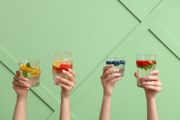 Many hands with infused water on green background