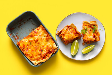 Baking dish and plate with tasty enchilada on yellow background