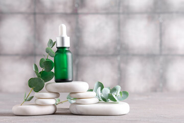 Spa stones and bottle of eucalyptus essential oil on grunge background, closeup