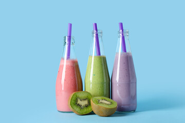 Bottles of different fresh smoothie with kiwi on blue background