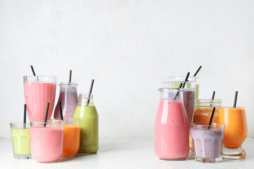 Glasses and bottles of different fresh smoothie on white background
