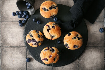 Black tray with tasty blueberry muffins on grunge tile background