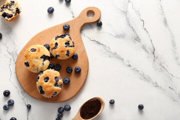 Wooden tray with tasty blueberry muffins on marble background