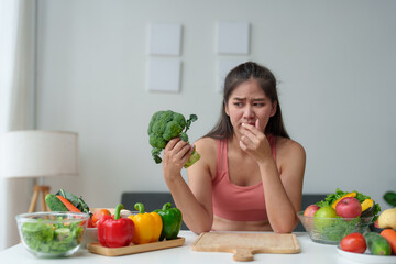 Beautiful Asian woman in exercise clothes. Fitness. Woman wants to control her healthy weight but doesn't want to eat fruits and vegetables. Useful salad dieting concept maintaining body shape.