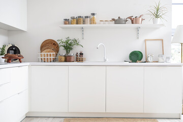 Interior of kitchen with white counters, shelf and utensils