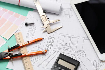 Architect's supplies with house plans and tablet computer on green background, closeup
