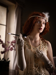 Beautiful model in 20s flapper dress holding a cigarette holder