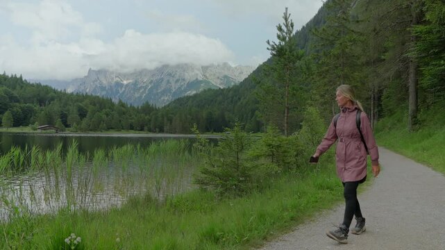 Tourist walks along lakeshore in Germany and takes picture of lake and mountains in the background, Ferchensee Germany