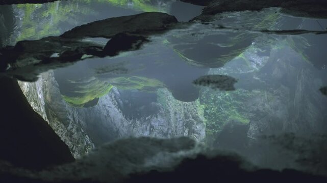 Tracking shot capturing the reflection of giant stalactites in the water at Son Doong Cave, Vietnam.