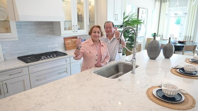 happy customers give a thumbs up symbol in the kitchen of their new home