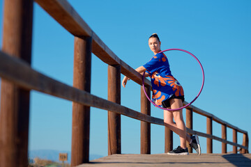 A performer showcases hula hoop skills along a coastal boardwalk