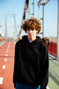 Young skateboarder on a bridge in the bright afternoon sun.