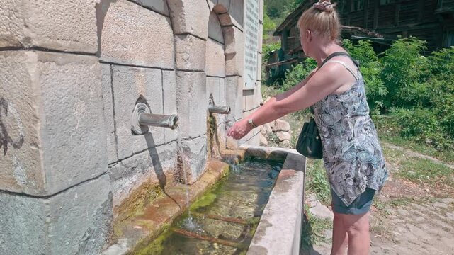 Woman cools down using free village refreshing drinking spring water