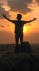 Fototapeta premium Silhouette of a Man Standing on a Rock at Sunset