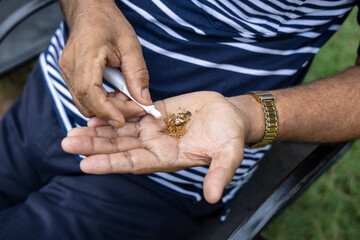 man using tobacco closeup shot at outdoor park at evening from flat angle