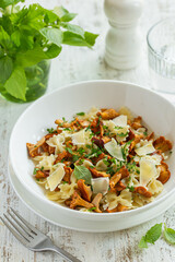 farfalle pasta with chanterelle mushrooms and cheese in white bowl