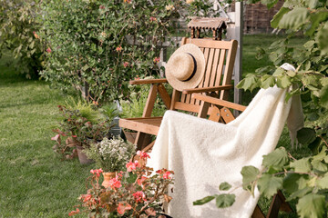 Garden wooden furniture on the lawn. Two wooden armchairs, next to vases with flowering plants. A...