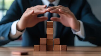 A businessman protects wooden blocks, symbolizing stability and strategy in work or entrepreneurship.