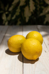 Three fresh lemons sitting on a table under the sunlight