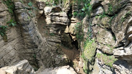 A stunning view of a rocky gorge, with layered stone formations and lush greenery. The natural textures of the rocks and the surrounding vegetation create a beautiful, untouched landscape.
