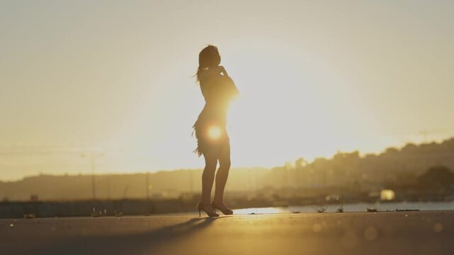 Woman gracefully performing a vibrant latin dance on the beach at sunset