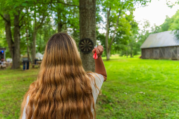 Girl is throwing darts in the nature. Children play