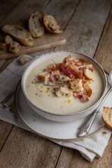 Vegetable creamy soup with crispy bacon,  croutons and sliced bread ready to eat