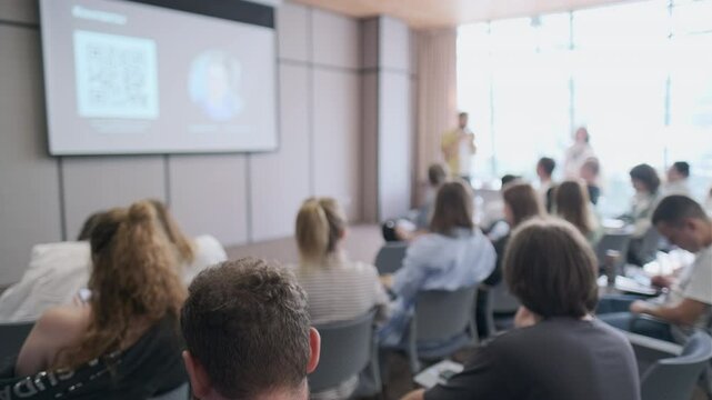 Group of people attending a business seminar, listening intently to a speaker in a modern conference room. The environment emphasizes learning, collaboration, and professional development.