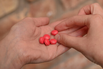 Ręka pełna czerwonych tabletek, uzależnienie od leków 