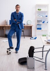 Young male employee playing football in the office