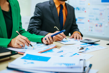 A group of professional business men and women are having a constructive meeting, discussing strategies, exchanging ideas and making decisions in a modern organization. They are wearing formal suits.
