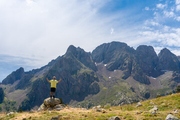 Hiker standing on a rock enjoying the views and the landscape with mountains, in Pirineos, Huesca...
