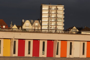 Vue du front de mer au Touquet Paris Plage, dans les Hauts de France, au Nord de la France. Alignement de portes colorées de cabines de bain.. Ciel gris bleu en arrière plan. Photo prise en mai 2024.