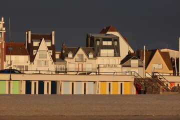 Vue du front de mer au Touquet Paris Plage, dans les Hauts de France, au Nord de la France. Alignement de portes colorées de cabines de bain.. Ciel gris bleu en arrière plan. Photo prise en mai 2024.