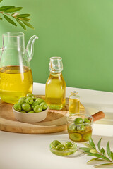Fresh green olives decorated with glass flasks containing olives oil displayed on wooden tray on a green background. Concept for advertising product with ingredient from olive extract