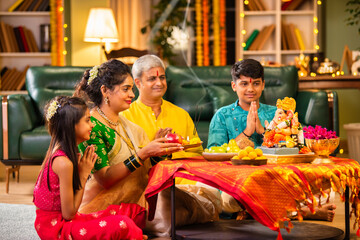 Indian family celebrating Ganesh Chaturthi, performing puja with traditional rituals and offerings