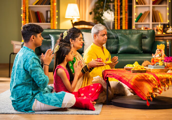 Indian family celebrating Ganesh Chaturthi, performing puja with traditional rituals and offerings
